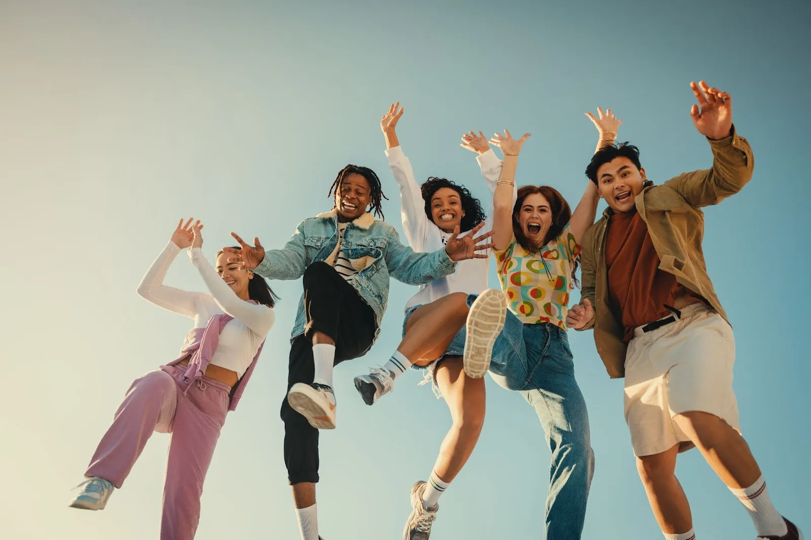 A group of young people joyfully jumping in the air, celebrating their participation in youth group activities and programs.