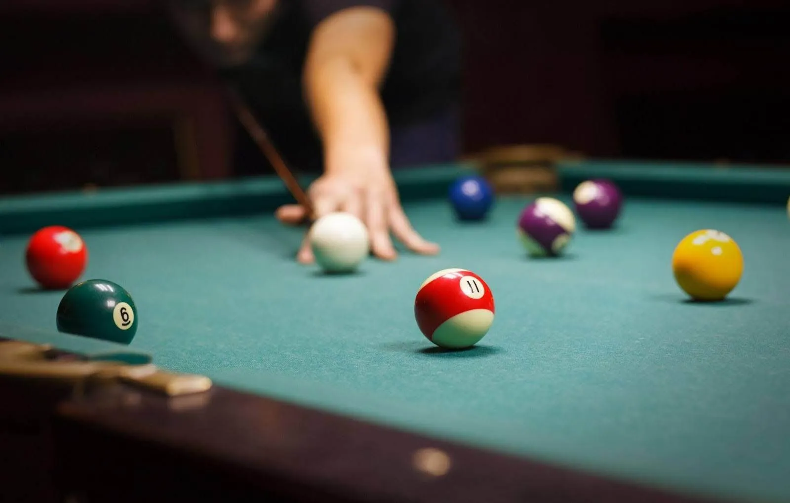 A man engages in a game of poolconcentrating on the various balls scattered across the table