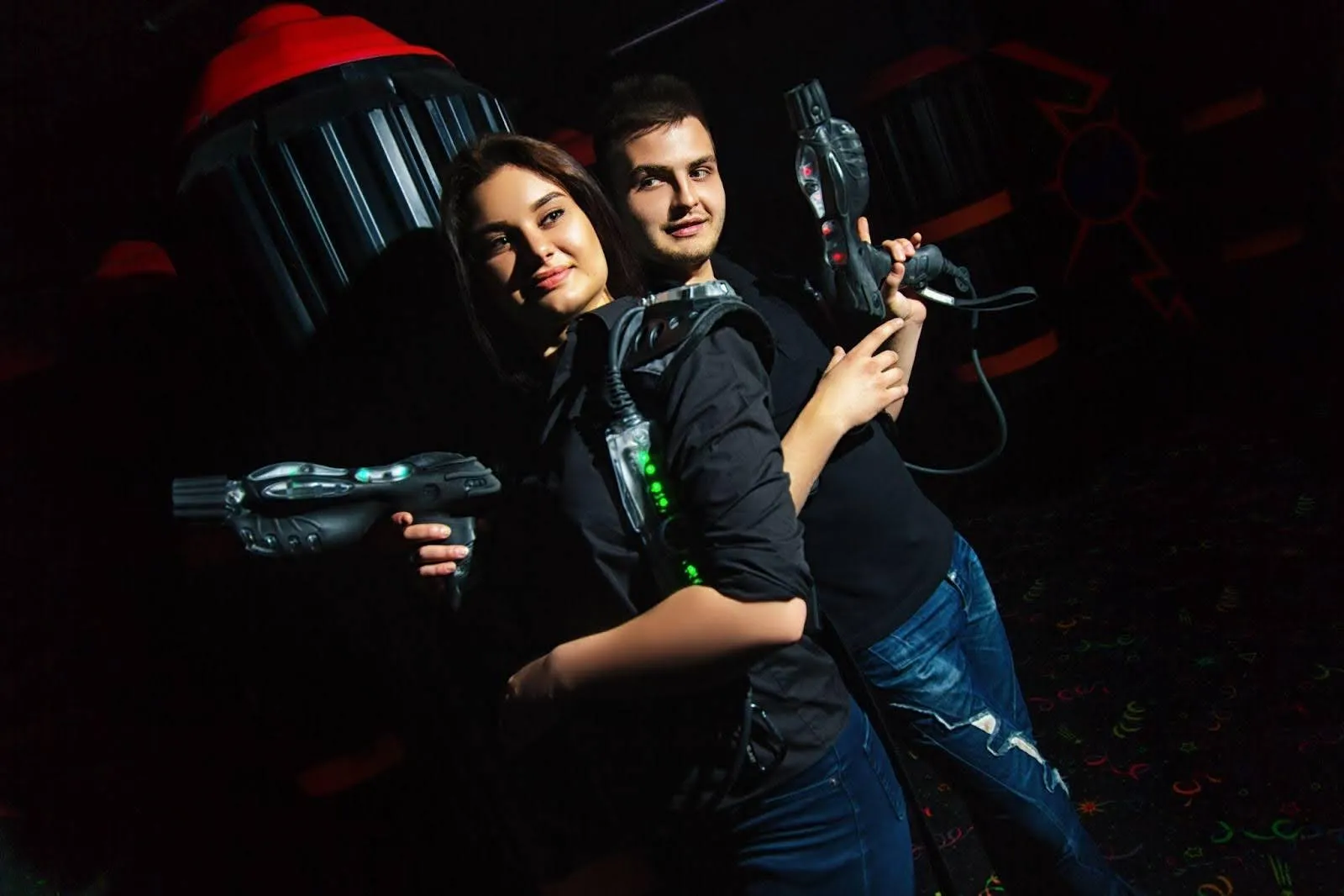 In a dark room, a man and woman grip guns indicating confrontation In a dark room, a man and woman grip guns indicating confrontation