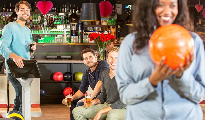 A group of people having a great time at a bowling alley, celebrating strikes and enjoying each other's company.