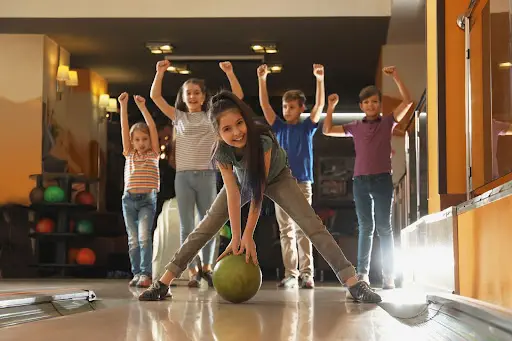 A group of children joyfully playing bowling at Skinny Dogz bowling alley, showcasing their excitement and teamwork.