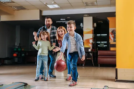 A family engaged in a lively bowling game at the alley