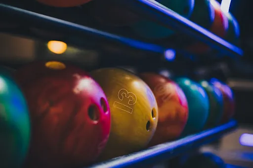 A selection of bowling balls neatly arranged on a rack in a bowling alley, ready for use by enthusiastic bowlers.