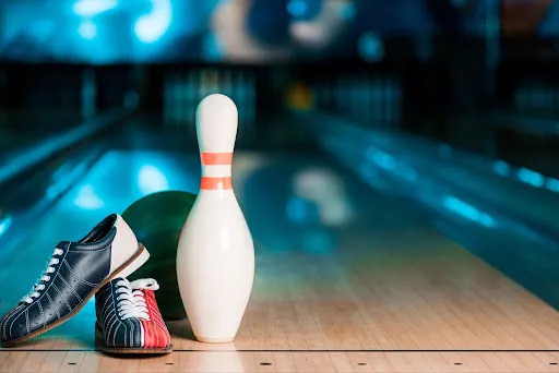 A pair of bowling shoes and a bowling ball positioned on a bowling lane, illustrating essential bowling tips for players.