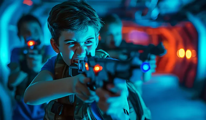 A young boy holding a gun in a dimly lit room.