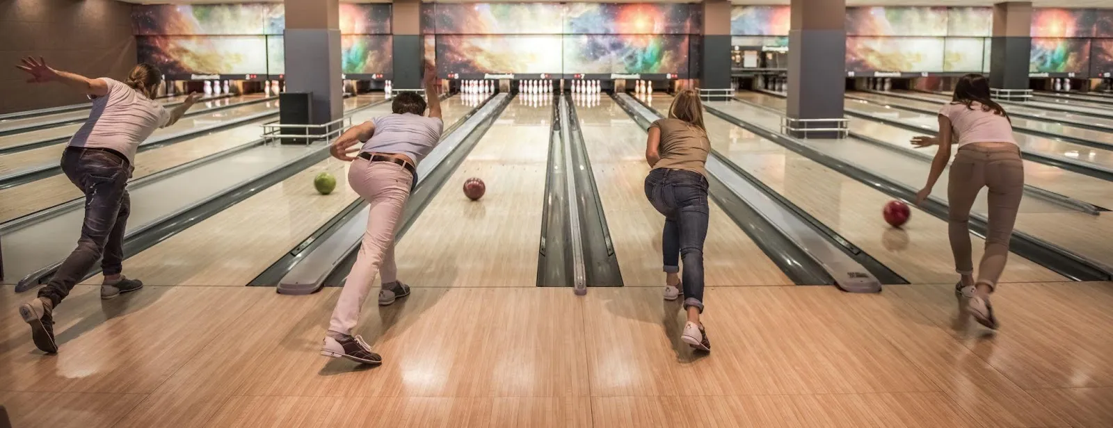 People of various ages and backgrounds having fun while bowling in a vibrant bowling alley.