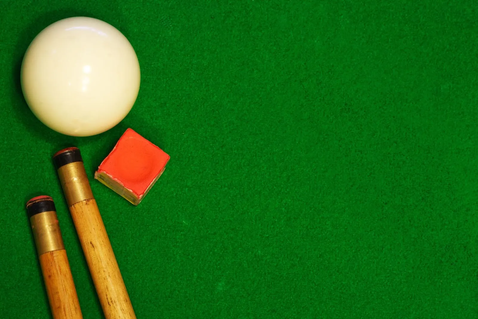 A pool cue and billiard ball on a green table, perfect for mastering billiards.