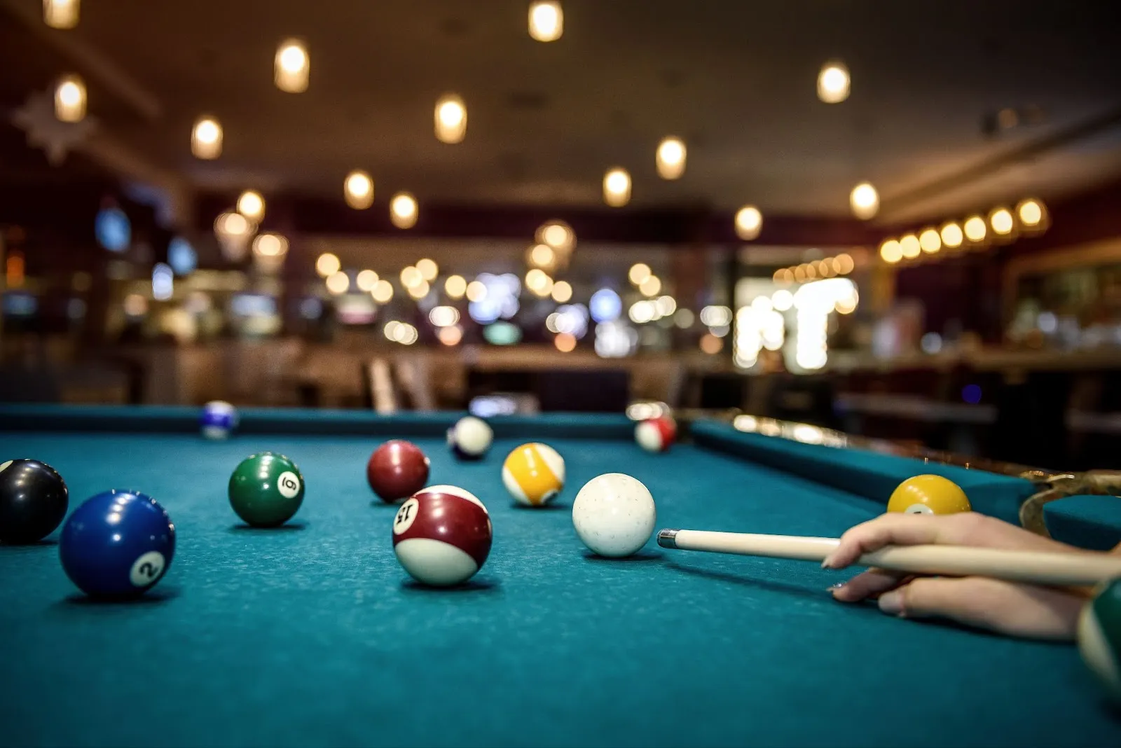 Skilled billiards player holding a cue stick, playing on a billiards table. Mastering the game of pool.