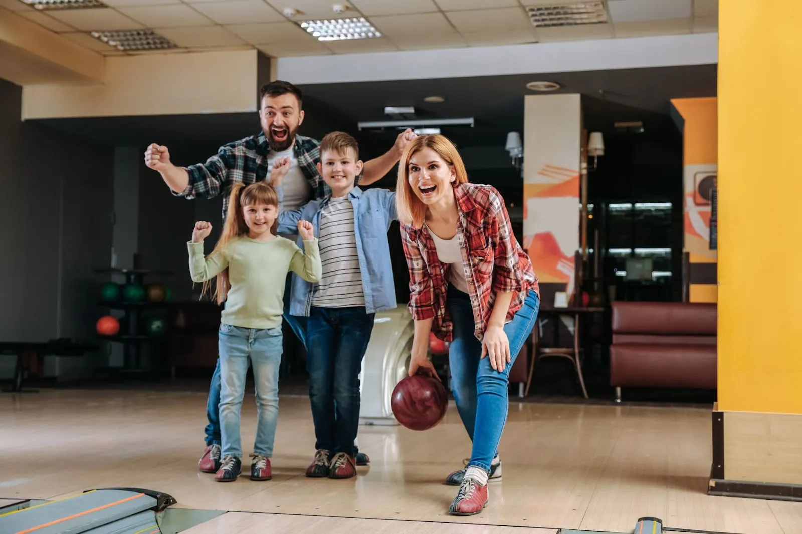 A family of four enjoying a game of bowling together at Skinny Dogz in Ogden, a fun family activity.