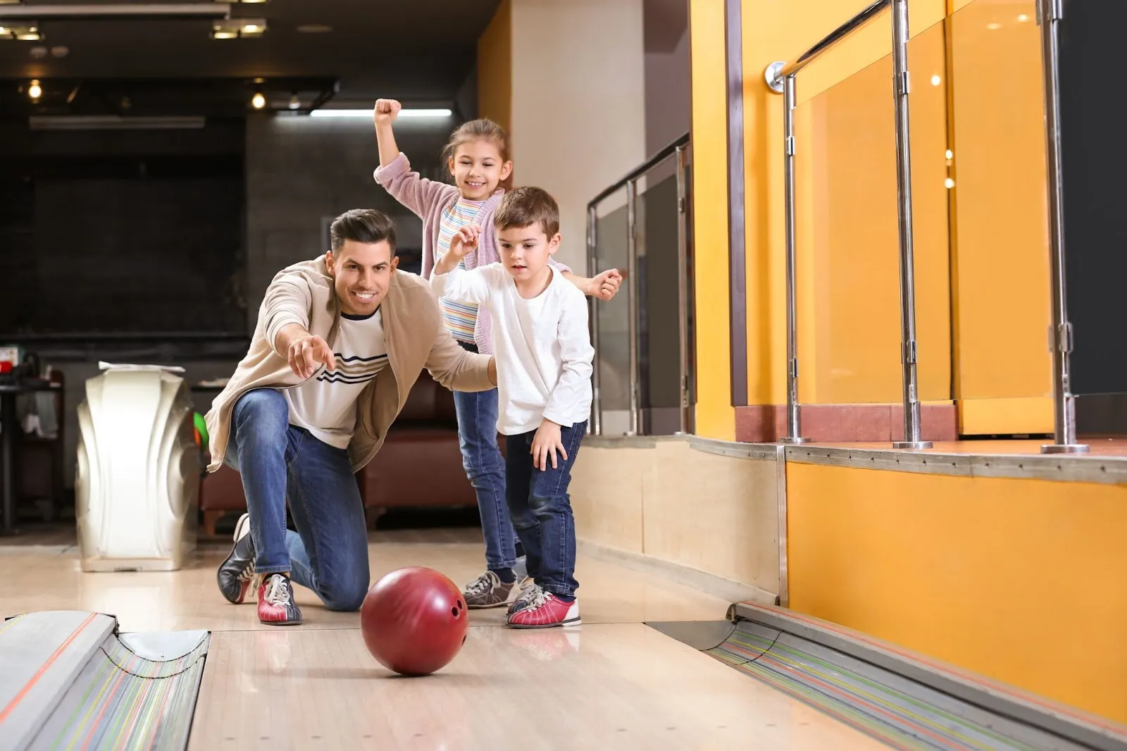 A man and two children enjoying a game of bowling at a family fun center.