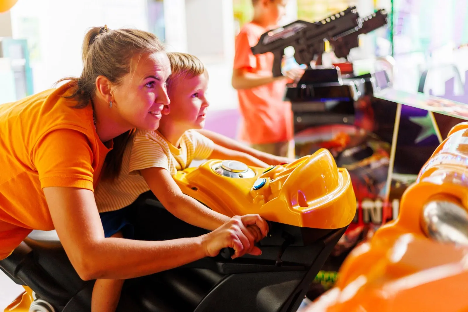 Woman and child enjoying arcade games at family fun center during a fun outing of bowling and laser tag.