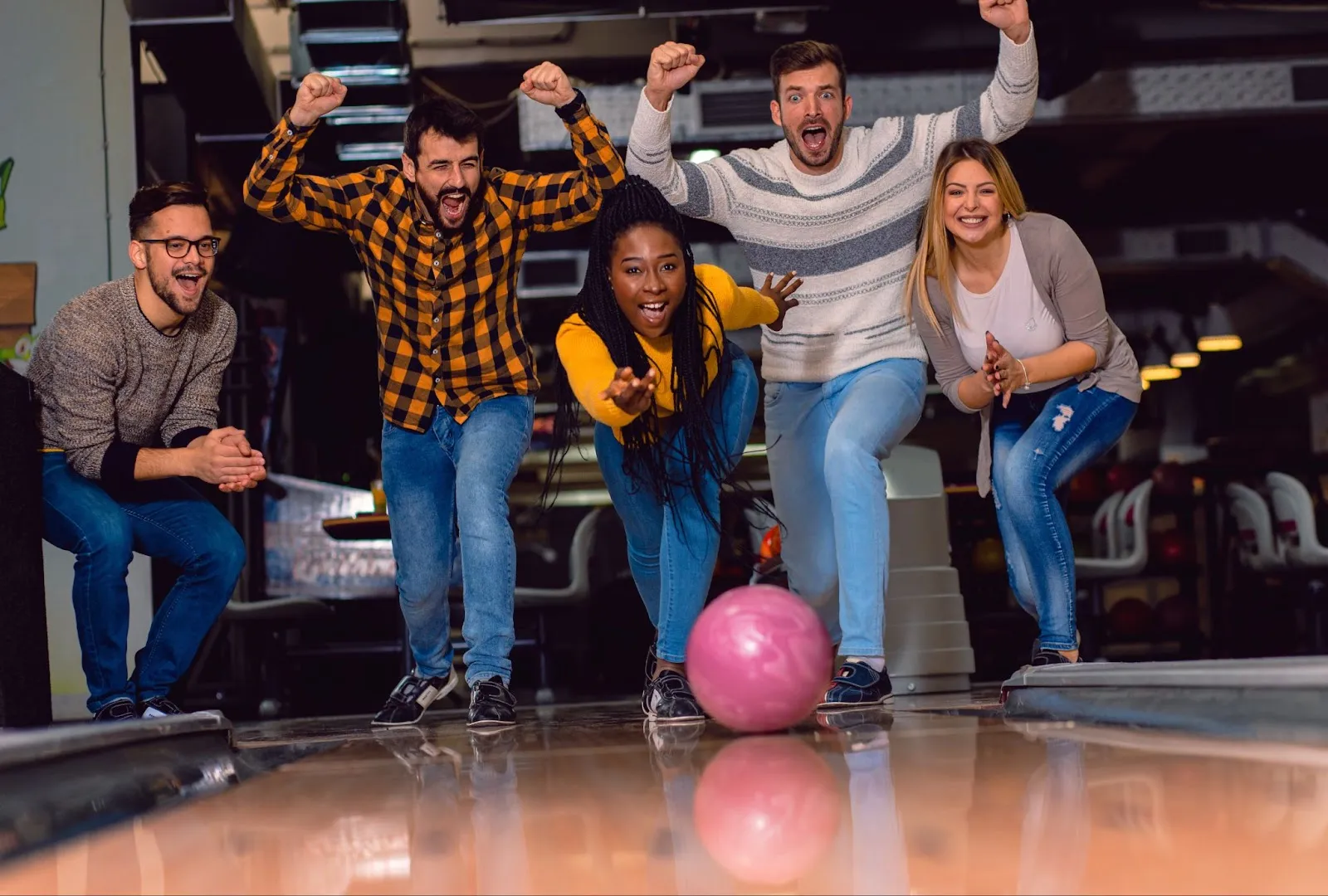 A group of colleagues enjoying a holiday corporate event while bowling together, with laser tag in the background.