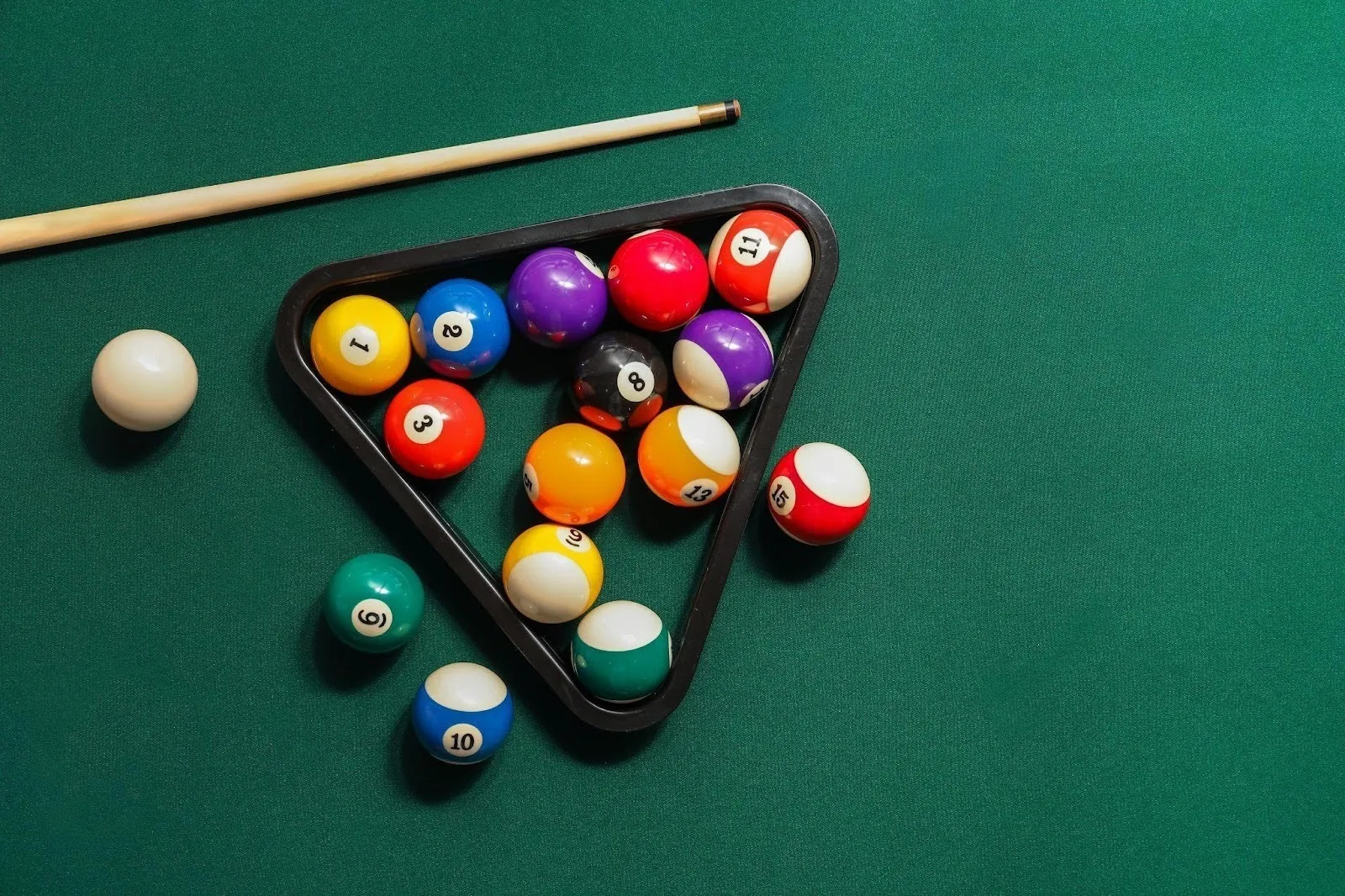 A collection of billiard balls and cue sticks arranged on a green felt table ready for a game of pool