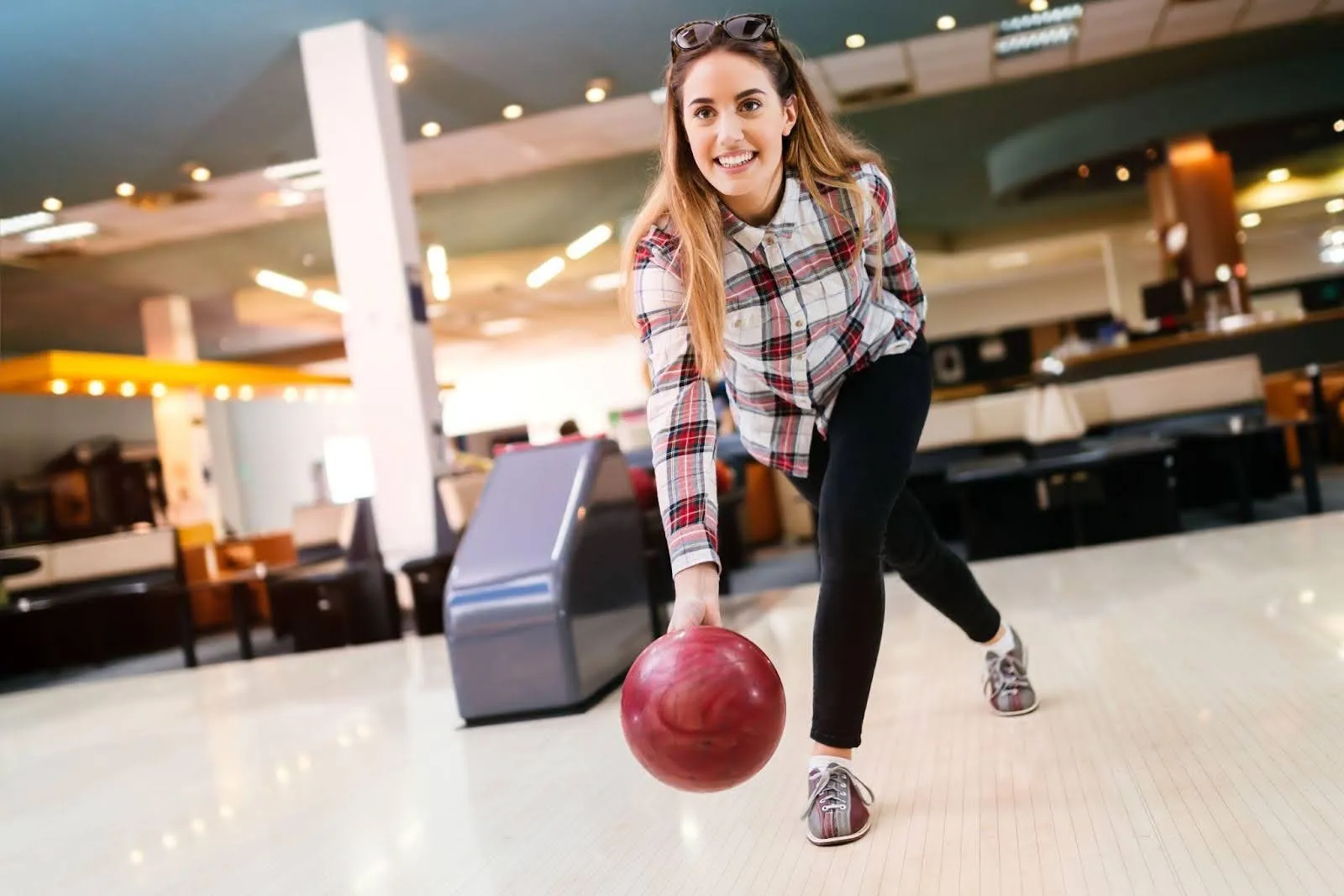 A woman bowls in a vibrant bowling alley her stance poised as she aims for the pins ahead