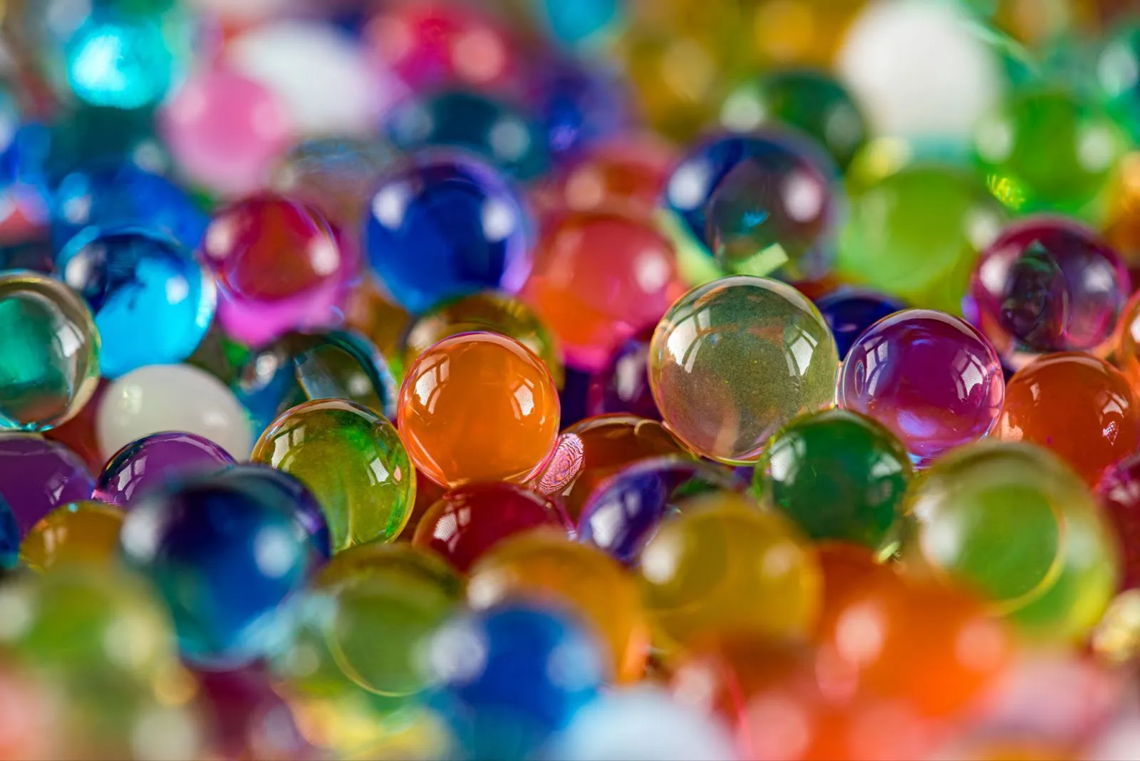 A close-up of colorful, shiny water beads reflecting light.