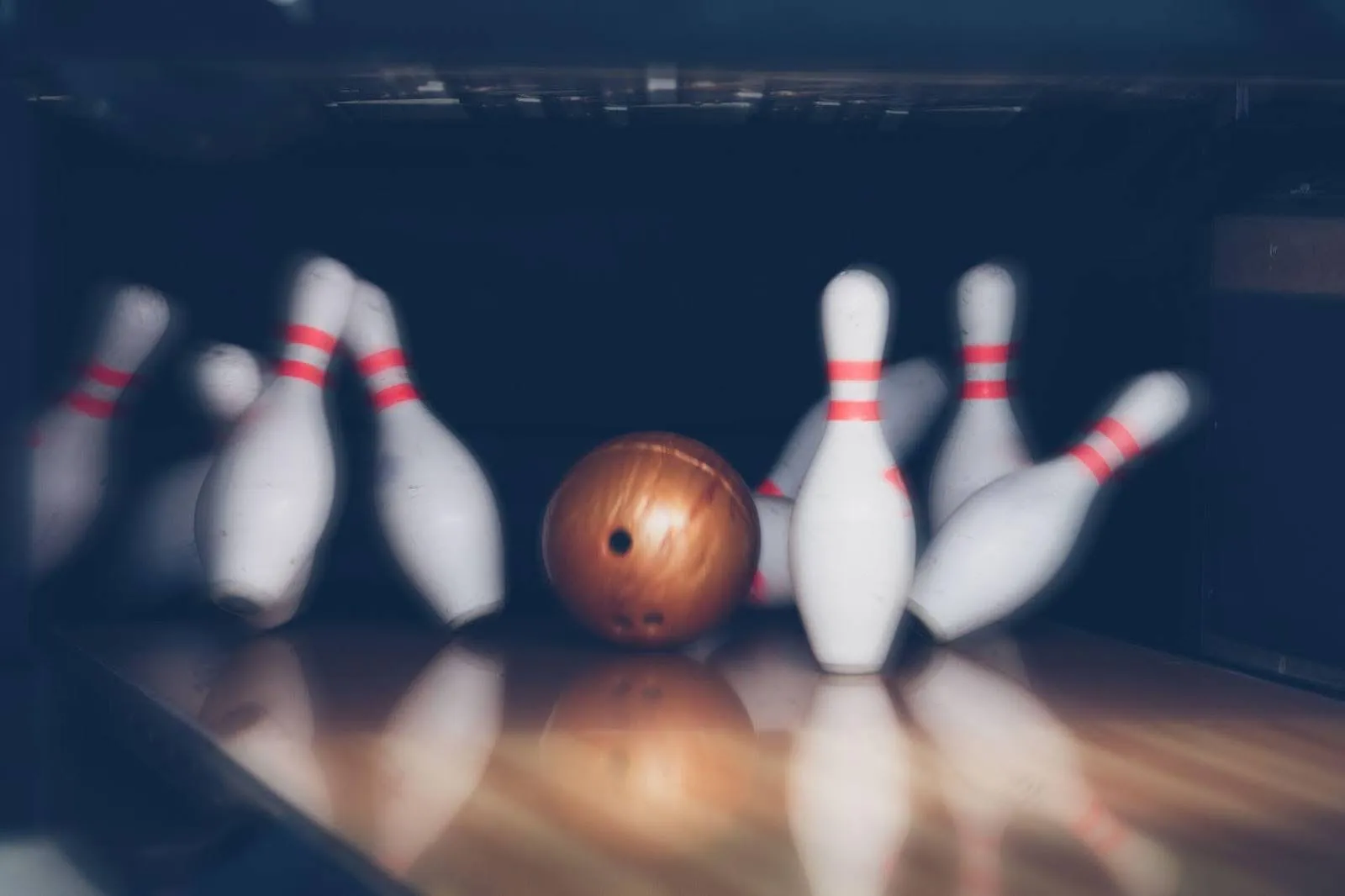 A bowling ball sits in the center of a well-lit bowling alley, ready for the next roll