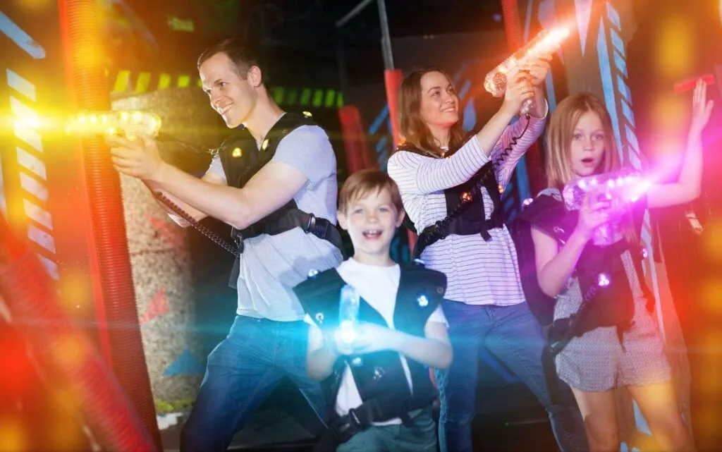 A cheerful family poses in a bright indoor laser tag venue
